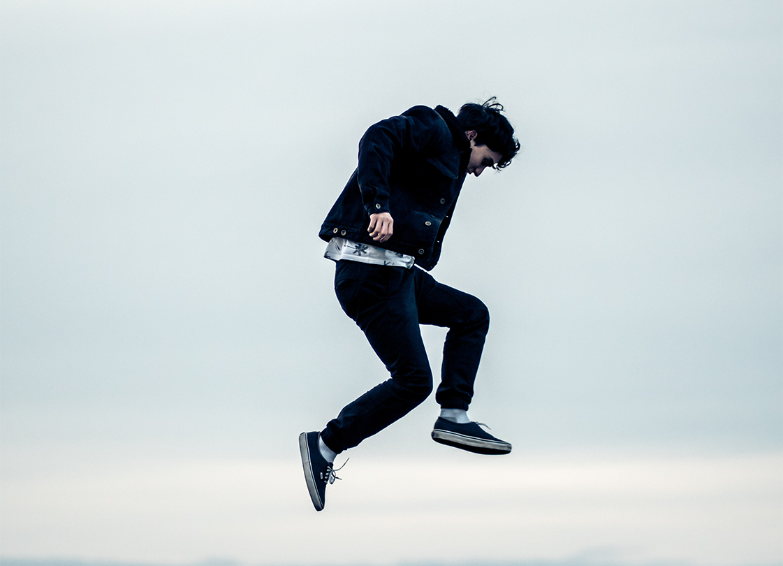 A young mman in black pants jumping up from the ground