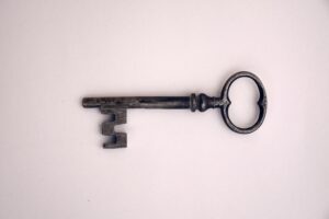 A old key laying on a light pink background